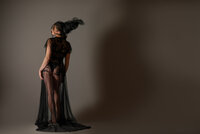 Dancer in a sheer black gown arching backward with her hair in motion against a warm brown backdrop.