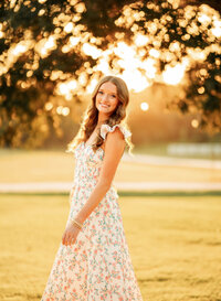Senior portrait in downtown Magnolia Springs, Alabama — standing sideways, but her face towards the camera.