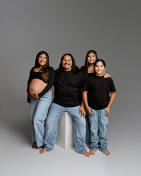 Studio maternity family portrait with expecting mother, father, and two children in coordinated outfits photographed by Kaitlyn Dawn Photography.