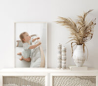 Framed baby portrait displayed as wall art above a styled dresser in a Niceville, Florida home