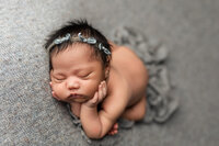 Newborn girl posed on a soft grey-blue backdrop during her studio newborn session near Mankato, Minnesota with Jennifer Brandes Photography.