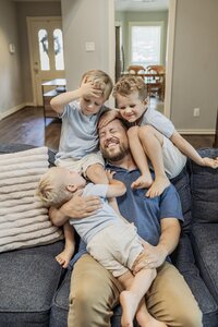 Three boys pile on top of their dad at an at home session