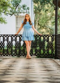 Senior portrait at the Malaga Inn in Mobile, Alabama— in a blue dress leaning against a black iron fence on the front porch.