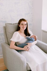 Mom holding her new baby boy and smiling at the camera
