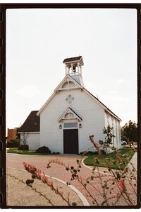 A classic white chapel for a small wedding with flowers in the foreground shot on color 35mm film in San Angelo.