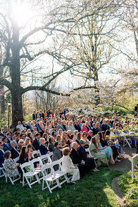 Guests seated outdoors beneath blooming spring trees, waiting for the wedding ceremony to begin at Burritt on the Mountain in Huntsville, Alabama, photographed by Perry Hancock.