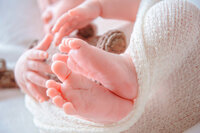 Close up of newborn baby feet wrapped in cream knit fabric