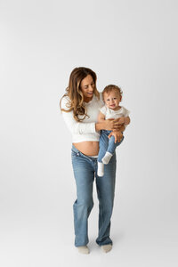 mother-to-be with toddler showing pregnancy during studio maternity session in los angeles