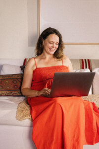 Woman on a laptop in bed during a telehealth appointment