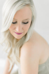 Close up photo of a woman wearing beige lace lingerie as she looks over her shoulder and smiles at a DFW photography studio.