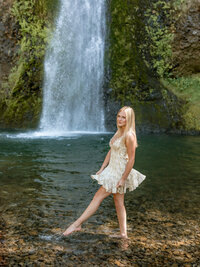 Oregon City high school gil taking her Senior Portraits at Horsetail Falls in the Columbia River Gorge wearing a yellow dress.