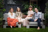 Family of four posing in their backyard for holiday photos