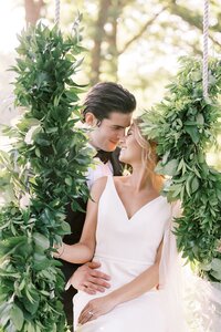 Shreveport wedding couple posing on a swing covered in greenery