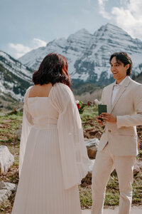 groom reads his vows to bride in front of colorado maroon bells