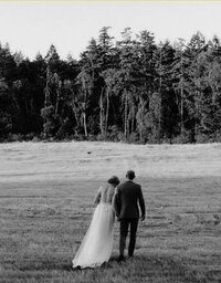 bride and groom walking in a grass field during golden hour