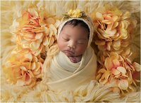 newborn wrapped in yellow, with flowers around