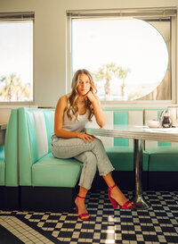Senior portrait at Sunliner Diner in Gulf Shores, Alabama — elbow on the table, wearing bright
pink heels.
