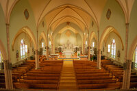 Interior of a Los Angeles church filled with warm yellow light, highlighting arches, aisle details, and ceremony atmosphere.