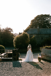 candid documentary wedding photographer captures bride walking at sunset at pengenna manor