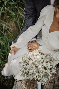 detail shot of bride sitting in a grassy field with a wedding bouquet captured by jackson hole photographers