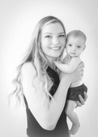 Young mother and her  baby girl cheek to cheek in a studio photo with a white background