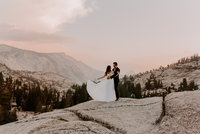 bride and groom standing on rock with mountain in background