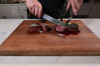 A person slicing two small steaks