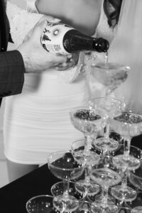 black and white image of man pouring champagne on tower of glasses in Detroit