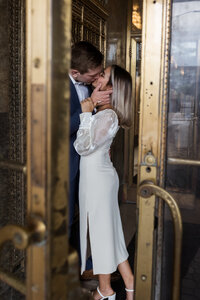 man and woman kissing in door at Fisher Building Engagement Photographer Savvy Shoots Photography