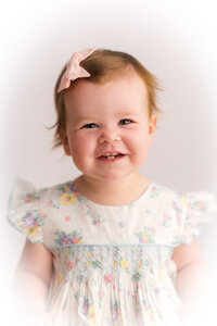 Baby girl smiles at the camera during her Heirloom Portrait Session at Holy City Babies Photo Studio in Charleston, SC.