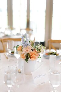 Reception table centerpiece with peach roses and blue delphinium by Flowergirl Cville at King Family Vineyard wedding | Photo by Paige Ryan Photography
