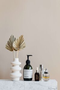 A collection on skincare products next to a white vase
