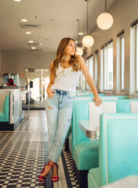 Senior portrait at Sunliner Diner in Gulf Shores, Alabama — standing beside a booth with legs
crossed, wearing bright pink heels.