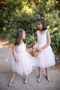 Two flower girls walking together at outdoor wedding