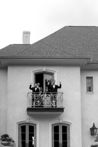 Groomsmen cheering from a balcony at a Huntsville wedding venue.