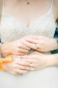 Detail photo of bride and groom putting on their rings before the brides dress