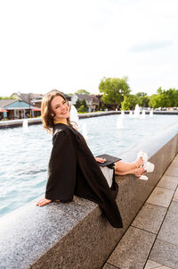 Senior girl sitting on the edge of the fountains outside of Belmont University Fine Arts College