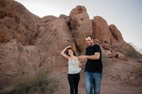 Couple posing on red rock formations at Papago Park during their engagement session