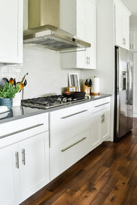A newly renovated kitchen with a modern stovetop and white cabinets