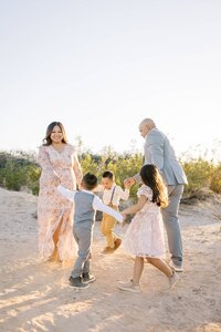 Collins family parents and children holding hands and playing together in the Las Vegas desert during golden hour, capturing a joyful candid family photography moment.
