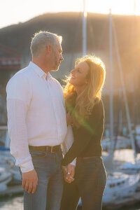 couple laughing by boats sunset engagement photos by the bay and golden gate bridge at cavallo point