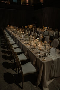 Longue table de réception dressée avec chandelles, fleurs blanches et vaisselle dorée, chaises capitonnées en enfilade au Théâtre St-James