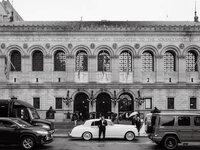 A wide black and white street scene in front of the Boston Public Library, capturing a genuine connection amidst the urban energy.