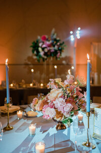 Pink floral arrangement sits on top of a fully set table