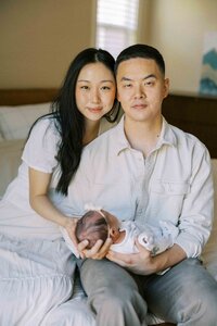 Classic newborn photography portrait with parents holding their baby girl