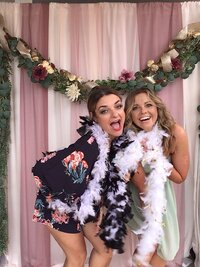 Bridesmaids in photo booth wearing boas and laughing together