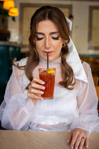 Bride drinks bloody mary looking down at cocktail