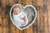 sleeping baby in heart shaped basket in Newborn studio photography in Oakland County