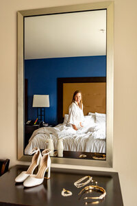 Bride getting ready in a Los Angeles hotel room, captured in a mirror reflection with soft natural light and documentary style.