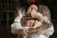 mom-newborn-chest-hold-window-light-white-blouse-in-home-boulder-photographer-273